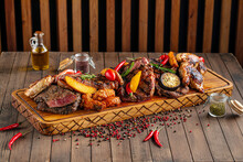 Side view on assorted grilled meat set on wooden serving board