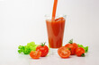 Glass of tomato fresh juice with raw tomatoes on light background