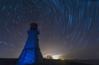 Lighthouse with night sky at background stars trails.