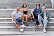 © Ivan Gener/Stocksy - Smiling young lgbt friends sitting on steps