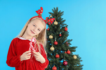 Cute little girl on blue background with Christmas tree