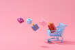 © Marc Tran/Stocksy - Shopping cart with flying gift box