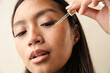 © Anna Tabakova/Stocksy - Beautiful model using face serum dropper
