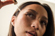 © Anna Tabakova/Stocksy - Beautiful model using face serum dropper