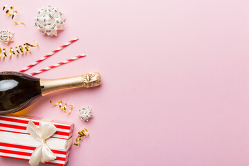 Wall Mural - Bottle of champagne with colored glitter, confetti and gift box space for text on colorfull background, top view. Hilarious, christmas and birthday celebration