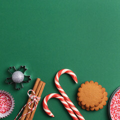 Christmas holiday green square background with empty space. Cookies, sweets, cupcake sprinkles from above.