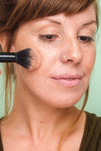 Close Up Of A Woman With Freckles Applying Make Up