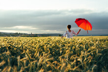 Woman Standing  With A Red Umbrella On Field Against Sky And Enjoying The Last Sunbeams