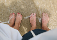 USA,California, Santa Monica, Bare Feet Of Man And Woman Standing Side By Side On Sandy Beach