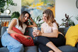© Studio Marmellata/Stocksy - Young women using smartphone on sofa