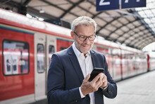 Male Professional Using Mobile Phone While Standing On Railroad Platform