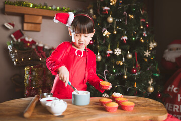 Wall Mural - young girl making Santa cupcake for Christmas party at home