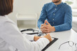 © Studio Romantic - Patient and doctor sitting at desk and talking. Man having conversation with professional physician at clinic or medical center. Close up shot. Concept of visit to doctor's office, clinic, or hospital
