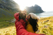 © Kike Arnaiz/Stocksy - Traveling couple taking selfie against sea