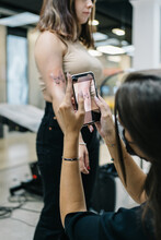 Woman Taking Photo Of Client Tattoo