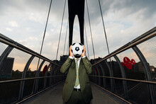 Businessman Covering Face With Soccer Ball While Standing On Bridge