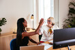 © BONNINSTUDIO/Stocksy - Cheerful diverse businesswomen giving high five