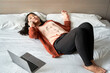 © Westend61 - Young businesswoman talking through mobile phone while lying by laptop on bed in hotel
