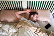 Mid Adult Man Sleeping By Mobile Phone In Bed