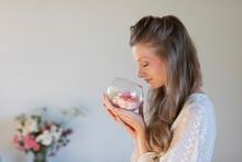 Beautiful Young Woman Smelling Scented Roses In Terrarium Bowl