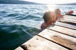 © Jennifer Bogle/Stocksy - Laughing siblings in lake cling to a dock