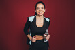 © Westend61 - Smiling sportswoman in sports clothing holding water bottle against maroon background