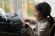 © Lauren Lee/Stocksy - Child reading what she typed on typewriter