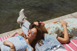Female friends relaxing on lap of man by river