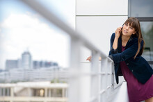 Young Female Professional Talking On Smart Phone While Leaning On Railing Looking Away