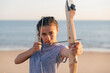 © Westend61 - Young woman practicing archery at beach