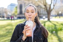 Young Woman Looking Cross Eyed While Drinking Milkshake At Park