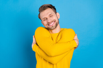 Poster - Photo of young guy happy positive smile dream dreamy embrace himself warm isolated over blue color background