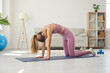 © Studio Romantic - Beautiful fit young woman having fitness and yoga workout at home. Caucasian girl practicing yoga on exercise mat and doing Cat and Cow pose to stretch and loosen her back and warm up her muscles