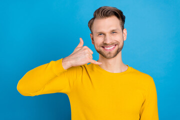 Sticker - Photo of young guy happy positive smile show finger call phone sign talk speak isolated over blue color background