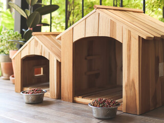 two empty wooden dog's houses with dog food bowls  in balcony decorated with houseplant in plant pot.