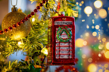 A Classic, British, Red Telephone Booth From England As A Christmas Ornament On A Illuminated Tree With Selective Focus