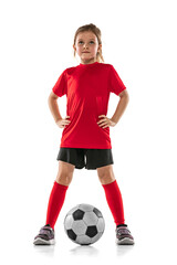 Wall Mural - Full-length portrait of girl, child, football player in red uniform training, posing isolated over white background