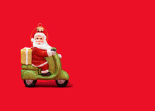 Christmas Ornament Of Santa Claus Riding Motor Scooter Against Vibrant Red Background