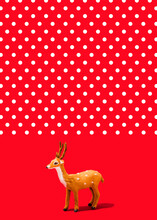 Studio Shot Of Reindeer Figurine Standing Against Vibrant Red Polka Dot Background