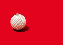 Studio Shot Of Single White-colored Christmas Ornament Lying Against Vibrant Red Background