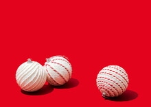 Studio Shot Of Three White-colored Christmas Ornaments Lying Against Vibrant Red Background