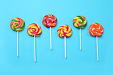 Fototapeta Tęcza - Sweet lollipops on light blue background, flat lay