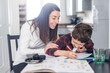 © Westend61 - Smiling mother assisting son doing homework at home