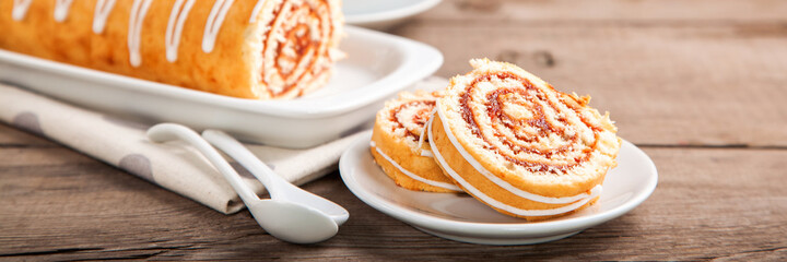 Wall Mural - Swiss roll with jam and tea on a table. Selective focus. Copy space.