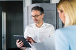 © Westend61 - Businessman using digital tablet while discussing with female coworker in office
