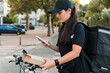 © Westend61 - Young female delivery person scanning package with smart phone