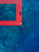 Man Sitting On Red Pier Over Sea At Thulusdhoo Island In Kaafu Atoll, Maldives