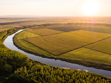 Aerial View Of Countryside River And Vast Agricultural Farm Fields At Summer Sunset