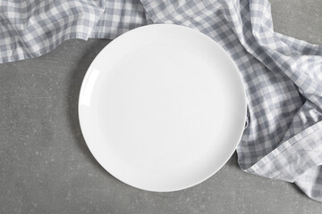 Empty white plate on gray stone table with checkered blue linen napkin. Flat lay, top view, copy space