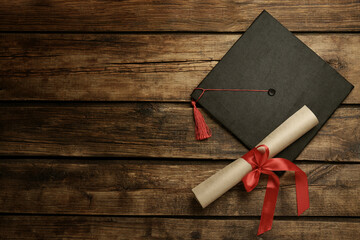 Wall Mural - Graduation hat and diploma on wooden table, flat lay. Space for text